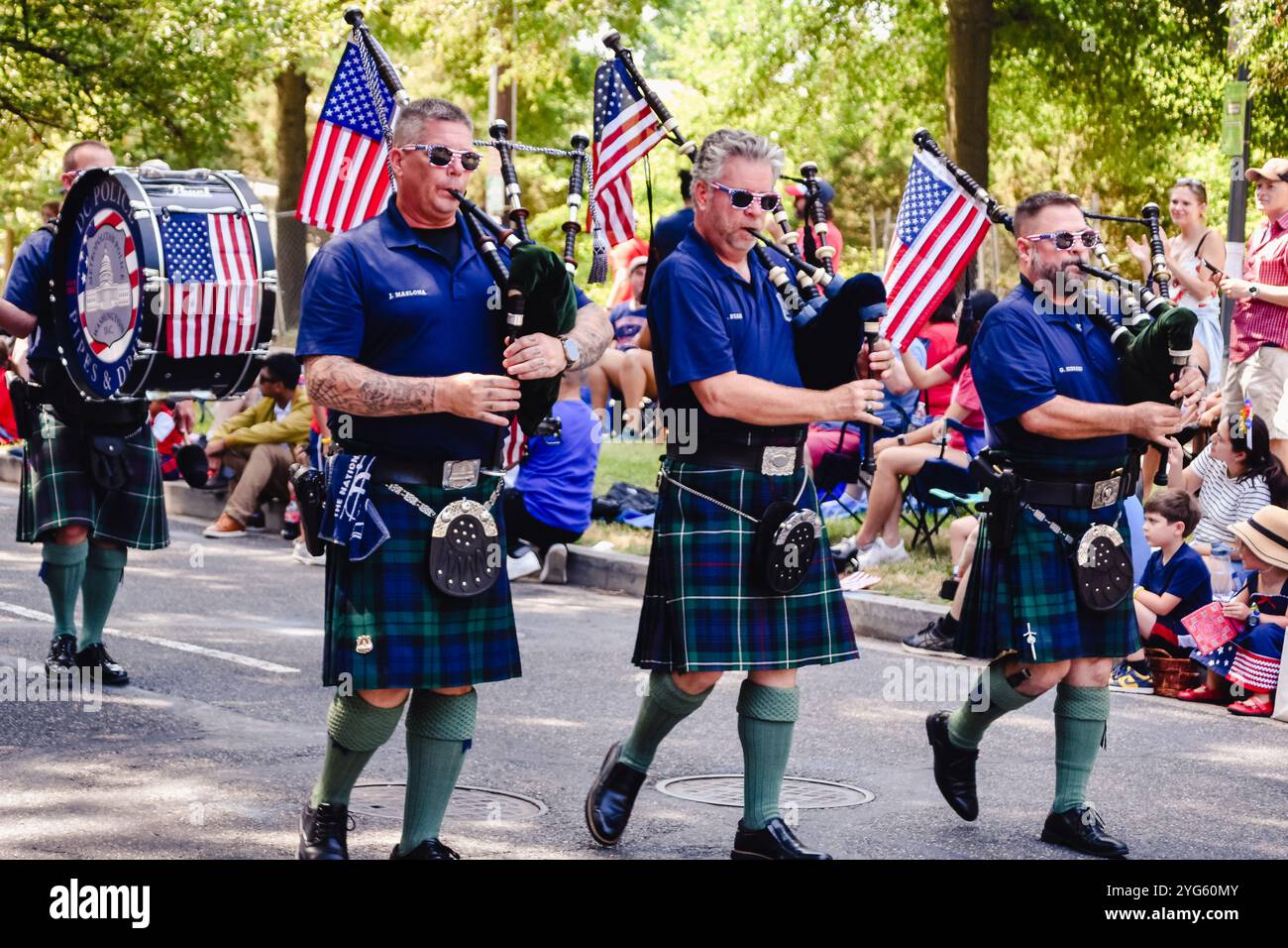 Three bagpipe players and bass drummer in kilts, marching in a parade